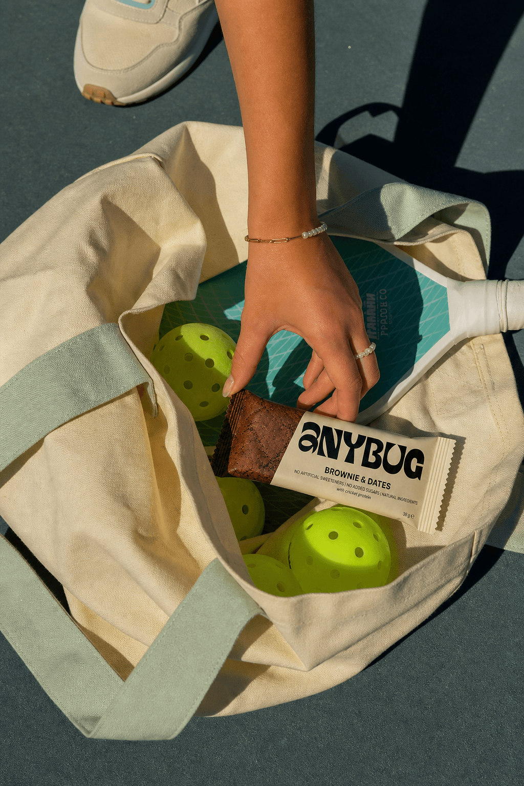 Barrita AnyBug en un tote con pelotas de pádel